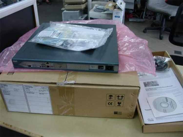 Cisco 2811 router unboxed with console cable, power cord, rack brackets, manual, and CD